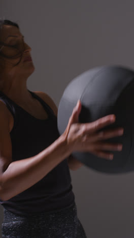 Vertical-Video-Studio-Shot-Of-Two-Mature-Women-Wearing-Gym-Fitness-Clothing-Training-With-Weighted-Medicine-Ball-Together